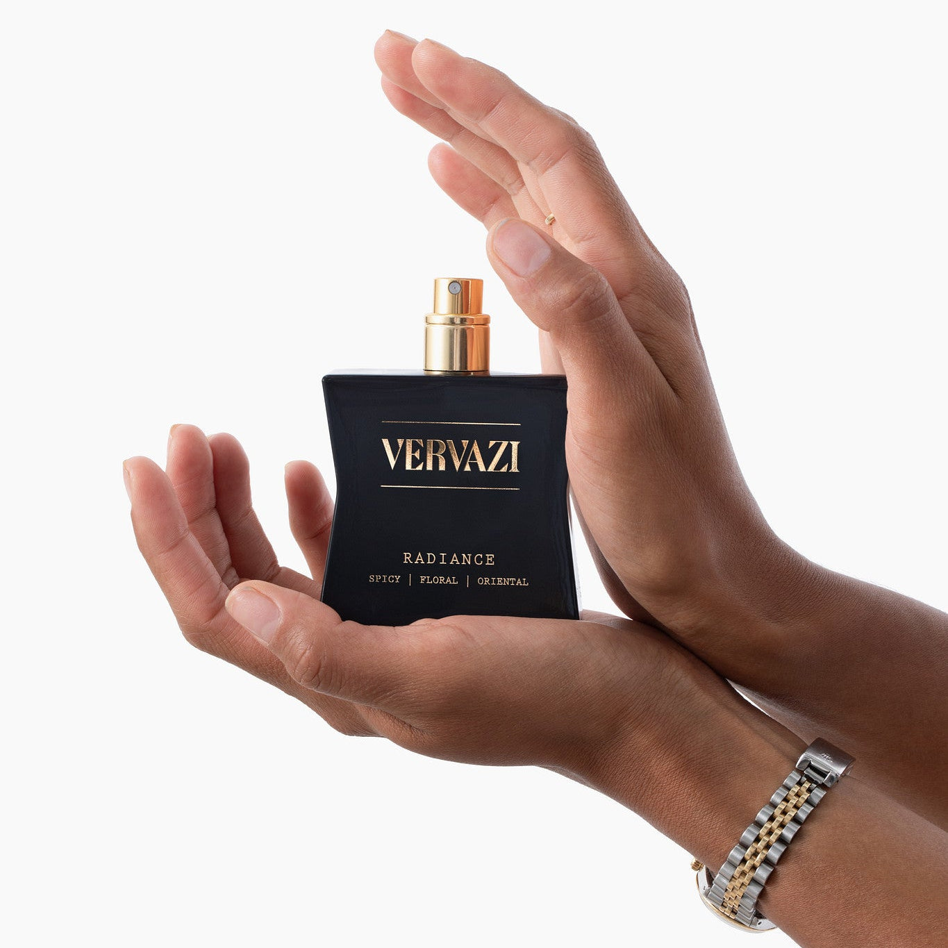 Hands holding a Vervazi radiance perfume bottle against a white background